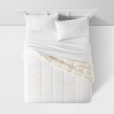 an unmade bed with white sheets and pillows