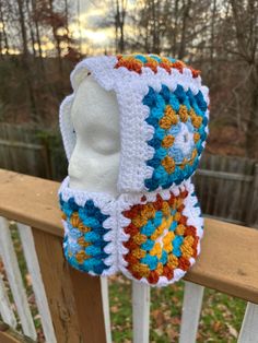 two crocheted hats sitting on top of a wooden fence