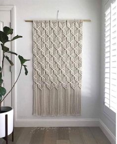 a white wall hanging next to a potted plant