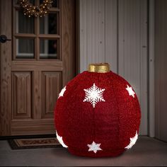 a red ball with white snowflakes on it sitting in front of a door