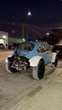 a blue and white car is parked on the side of the road at night time