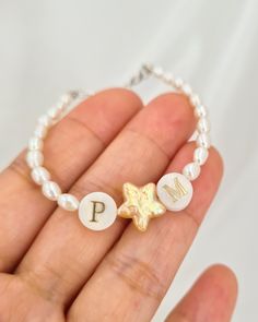 Add a touch of celestial elegance with this beautifully crafted bracelet, featuring a harmonious blend of freshwater rice pearls and a charming star-shaped pearl. Accented with two mother-of-pearl letter beads, this bracelet offers a personalized flair that makes it truly special. The centerpiece arrangement of letter, star, and letter beads can symbolize messages like "I ★ U" or "E ★ K," adding a unique and heartfelt touch. The bracelet is completed with a 925 sterling silver adjustable clasp, Star-shaped Letter Beads Bracelets As Gift, Star-shaped Letter Beads Bracelets For Gift, Star-shaped Letter Beads Bracelet As Gift, Star Shaped Letter Beads Bracelets For Gifts, White Charm Bracelet With Star Charm As Gift, Star-shaped Jewelry With Pearl Charm As A Gift, Star-shaped Jewelry With Pearl Charm Gift, White Dainty Pearl Bracelet For Birthday, Dainty White Pearl Bracelet For Birthday