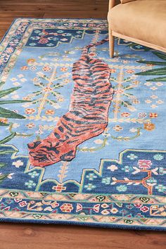 a blue rug with a tiger design on the top and bottom, in front of a chair