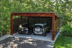 two cars are parked in a carport on the side of a road near trees