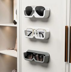 three pairs of sunglasses are mounted to the side of a white cabinet with eyeglasses on it