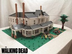 a lego model of a house with trees and people on the lawn in front of it