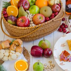 a basket filled with lots of different types of fruit next to plates and bowls full of food