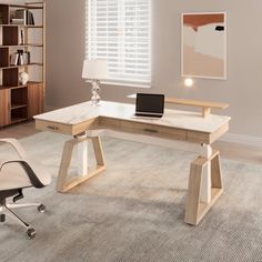 a desk with a laptop on it in front of a bookcase and chair next to a window