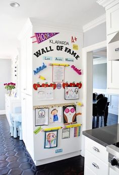 a white refrigerator freezer sitting inside of a kitchen next to a wall with pictures on it