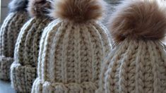 several knitted hats with pom - poms on them