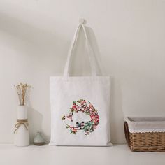 a white tote bag sitting on top of a shelf next to a basket and vase