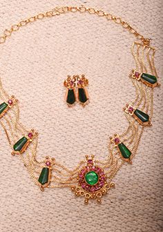 Add a touch of traditional elegance to your collection with this Gold Tone Kerala Style Pink-Green Nagapadam Choker Combo Necklace Set. Featuring a striking choker adorned with intricate nagapadam motifs, this piece beautifully combines rich pink and green hues for a vibrant, eye-catching look. The gold tone enhances its luxurious appeal, making it perfect for weddings, festivals, and special occasions. Accompanied by matching earrings, this set offers a cohesive look that effortlessly elevates any outfit. Embrace the charm of Kerala's artistry and make a stunning statement with this exquisite necklace set Note: This jewelry has no precious metals or stones. *Note: The earrings have thick stems* Note: Some of the pics are close up shots to show detail and may make the product appear larger Exquisite Luxury Earrings For Festive Occasions, Luxury Gold Blazer For Festive Occasions, Luxury Women's Choker For Festivals, Luxury Gold Choker For Festivals, Luxury Gold Choli For Festivals, Luxury Festive Choker Jewelry Set, Luxury Statement Choker For Festive Occasions, Luxury Festive Statement Necklaces, Luxury Gold-tone Choker Necklace