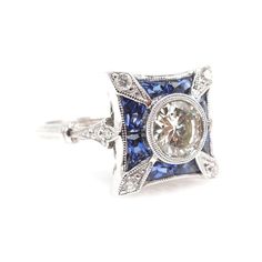 This stunning Art Deco style ring is the perfect ambassador of the period's elegant rectilinear design elements. Centered with an 0.85ct Old European cut diamond, the bezel set center stone is surrounded by a flourish of French cut sapphires and diamonds. The undercarriage is beautifully filigreed and the narrow shoulders of the ring widen to a 2mm wide double half round shank.CENTER STONE: 0.85 ct Old European cut diamond - J color, VS2 clarityMETAL: 18K White GoldSIDE STONES: Diamonds (F-G col Diamond Cut Sapphire Ring With Cushion Shape, Exquisite Sapphire Ring With Single Cut Diamonds For Anniversary, Platinum Sapphire Ring With Radiant Cut, Formal Asscher Cut Sapphire Ring In Diamond White, Luxury Sapphire Diamond Ring With Diamond Cut, Classic Platinum Sapphire Ring With Radiant Cut, Exquisite Diamond White Sapphire Ring With Diamonds, Classic Gia Certified Rectangular Sapphire Ring, Radiant Cut Sapphire Ring In Platinum