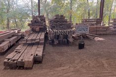 there are many logs stacked on top of each other in the dirt near some trees