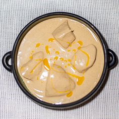 a bowl filled with some kind of food on top of a white tablecloth covered table