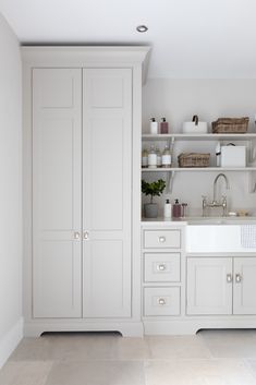 an all white kitchen with open shelving and sink