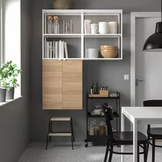 a kitchen with white cabinets and black chairs next to a dining room table in front of a window