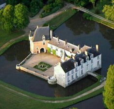 an aerial view of a large castle like building in the middle of a lake surrounded by trees