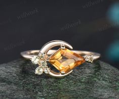 a ring with an orange topazte surrounded by white diamonds on a green rock