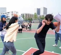 a group of people playing basketball on a court with buildings in the backgroud