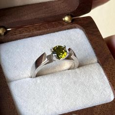 a ring in a wooden box with a yellow stone on it's center piece