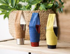 three different colored vases sitting on top of a table next to a potted plant