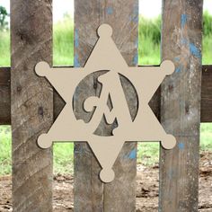 a wooden sign with the letter aa on it sitting in front of a wood fence