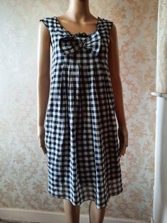 "Vintage smock style dress in black and white  gingham.  There is a small ruffle at the neck line and a large bow,  small pleats with the dress flaring from the bust.  It has no sleeves and is lined in black cotton. Bust;   32\" Length from shoulder;      35\"      Made by   MADAME A PARIS        100%  cotton" Casual Plaid A-line Dress, Summer A-line Plaid Dress, Chic Cotton Sundress For Picnic, Bohemian Smock Dresses For Summer, Spring Gingham Sundress With Ruffles, Picnic Gingham Sundress With Ruffles, Chic Cotton Dress For Picnic, Vintage Plaid Dress For Spring, Vintage Plaid Mini Dress For Summer