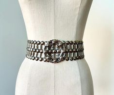 1960s mod adjustable statement belt in silver metal with a stunning circular buckle. The belt is adjustable up to 31". The belt is in excellent condition with two metal hooks on the back side of the buckle closure for an adjustable fit. An incredibly special piece to add to your wardrobe to dress up any look from a silk slip dress to cinching a jumpsuit or evening gown, this gorgeous belt is a real treasure! 31.5" long by 2.5" wide and 2.75" at buckle. Please message with any questions. Luxury Silver Metal Chain Belt, Modern Silver Belt For Formal Occasion, Luxury Silver Chain Belt For Formal Wear, Luxury Silver Chain Belt For Formal Occasions, Vintage Silver Chain Belt For Party, Chic Silver Metal Chain Belt, Formal Silver Chain Belt, Vintage Adjustable Metal Belt, Luxury Adjustable Silver Belt Buckles