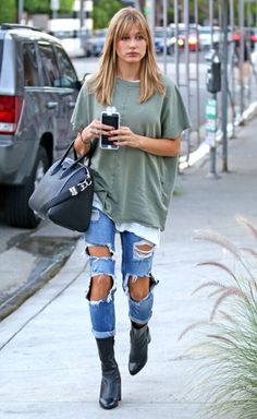 a woman walking down the street while holding a cell phone