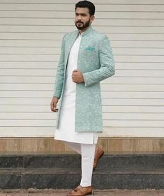 a man wearing a white and blue sherwa is standing in front of a building