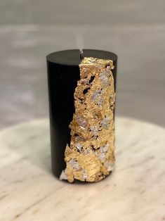 a candle that is sitting on top of a marble table with gold leafy decorations