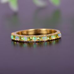 a yellow gold band with green and white opal stones on it's sides