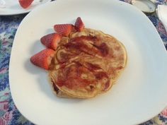 a plate topped with pancakes and strawberries on top of a blue tablecloth covered table