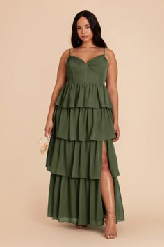 a woman wearing a green dress with tiered layers and a slit down the side