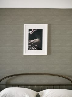 a bed with white pillows and a framed photograph on the wall