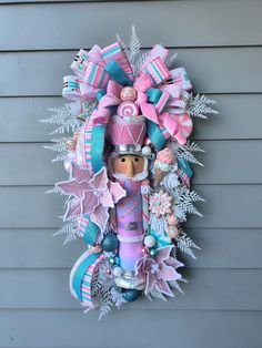 a pink and blue christmas wreath on the side of a house