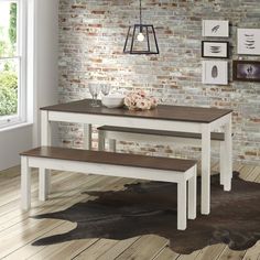 a white table with two benches in front of a brick wall and wooden flooring