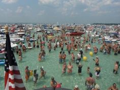 a large group of people in the water at a boat dock with many boats and an american flag