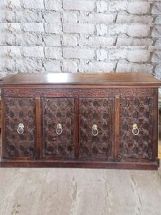 an old wooden chest with four drawers and two knobs on the front, sitting against a brick wall