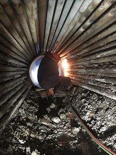 the inside of a metal pipe with some wires attached to it's sides and an orange light shining in the middle