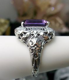 Natural Purple Amethyst Ring Intricate Design#149 Custom Made Inspired by Victorian era designs, I now offer this lovely filigree reproduction in sterling silver. This is a flawless natural purple amethyst is 12mm by 10mm in Length & Width. The ring is 3/4th of an inch North/South on the finger. The inside of the band is etched 925. Notice the intricate and detailed Victorian design of the antique patina silver filigree setting all the way down the band. This is an exquisite rendition of an Elegant Purple Amethyst Ring With Intricate Design, Purple Promise Ring With Intricate Design, Purple Intricate Design Promise Ring, Amethyst Rings With Intricate Design For Wedding, Purple Hallmarked Art Deco Amethyst Ring, Purple Anniversary Rings With Intricate Design, Art Deco Purple Amethyst Ring, Antique Purple Amethyst Ring With Accent Stones, Purple Amethyst Ring With Intricate Design For Promise