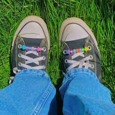 a pair of shoes with colorful beads on them sitting in the grass next to someone's feet