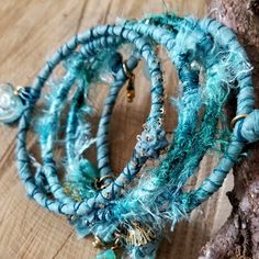 three bracelets with beads and charms on top of a wooden table next to a tree