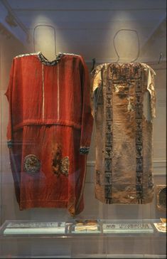 two ancient clothing are on display in a glass case