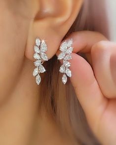 a close up of a person wearing a pair of ear clips with diamonds on them