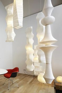 a room filled with lots of white lamps hanging from the ceiling next to a table and chairs