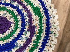 multicolored braided rug on wooden floor with white and blue circles in center