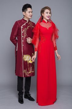 a man and woman standing next to each other wearing red dresses with gold embroiderys