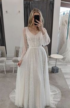 a woman taking a selfie while wearing a wedding dress in front of a mirror